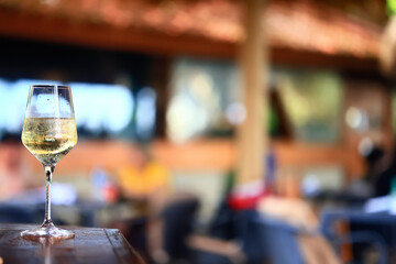 a glass of white wine served in a restaurant, abstract background of a summer restaurant