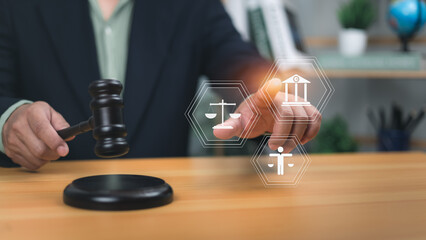 Human holding gavel pointing to holographic icons scales of justice, government building, and person. Symbolizes legal system, human rights, the rule of law for justice and regulatory compliance now.