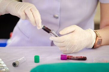 Nurse wearing white medical gloves is drawing blood from patient's arm for examination or PRP procedure. Concept of laboratory research, medicine, analysis.