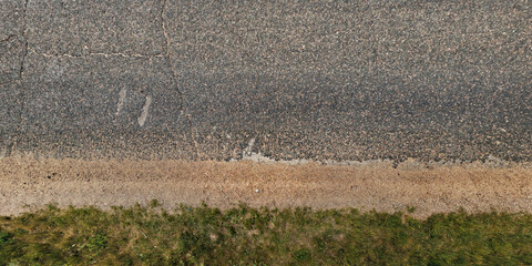 top view of textured asphalt road with median strip and grass lawn