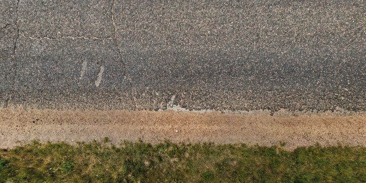 Fototapeta top view of textured asphalt road with median strip and grass lawn