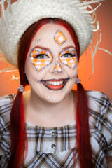 Creative Junina makeup with plaid patches, red braids, and a straw hat. A cheerful, festive look inspired by traditional Brazilian culture.