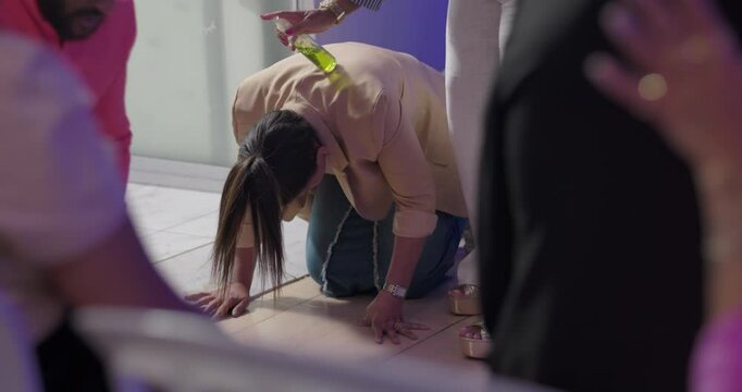 Woman kneeling on floor during evangelical service, emotional act of surrender, preacher anoints her back with oil as Hispanic and Latin worshippers observe in silence