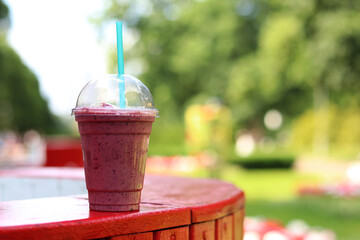 Berry milkshake with ice cream. Summer drink in disposable plastic cup with straw. Coffee with ice...