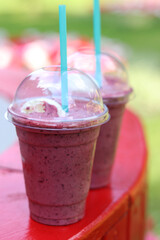 Berry milkshake with ice cream. Summer drink in disposable plastic cup with straw. Coffee with ice...