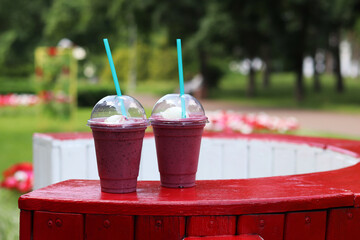 Berry milkshake with ice cream. Summer drink in disposable plastic cup with straw. Coffee with ice...