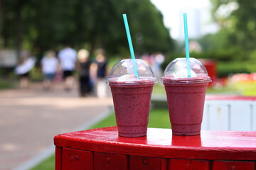 Berry milkshake with ice cream. Summer drink in disposable plastic cup with straw. Coffee with ice...