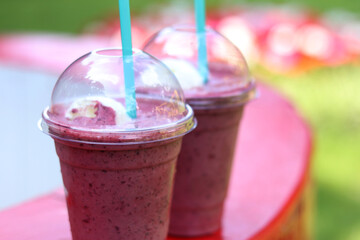 Berry milkshake with ice cream. Summer drink in disposable plastic cup with straw. Coffee with ice...