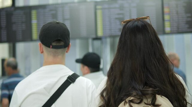 Man and a woman are looking at a large screen with a lot of information on it. They are both wearing sunglasses