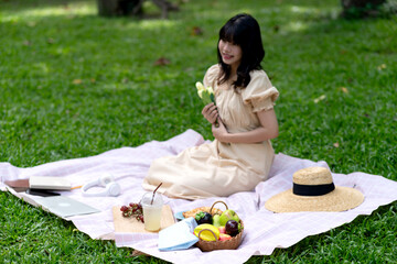 Smiling woman with book are sitting on the green grass in the park