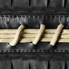 Seamless 4k photo texture material of black leather with rope insert and stitches.
