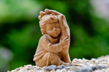 Kind im Schutz der Hand auf Kiesbett mit grünem Hintergrund,  Child protected by hand on gravel bed with green background