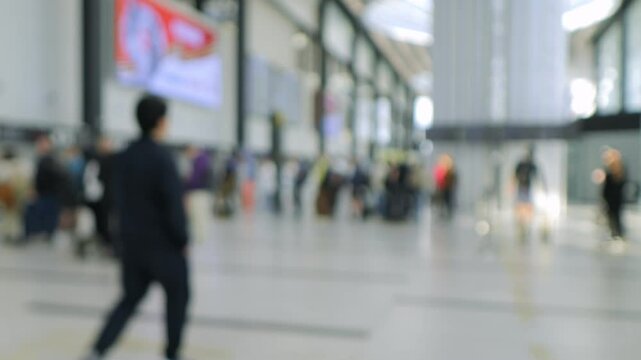 Busy airport terminal with people walking around and carrying luggage. The atmosphere is bustling and hectic