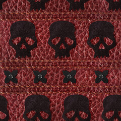 Seamless 4k photo texture material of red colored stitched leather with skull insterts.