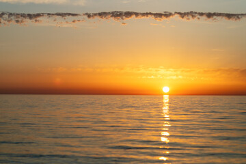Beautiful golden sunset over calm sea water with sun reflection on horizon