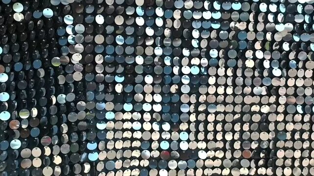 Silver sequins on the wall in close-up, which move in the wind. Stylish sequin texture