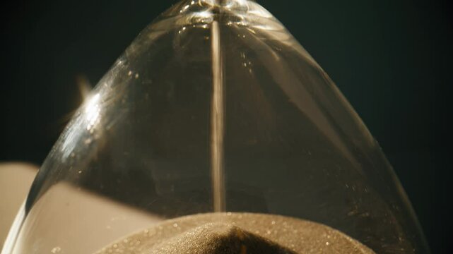 Macro view elegant hourglass in evening light. Closeup gold sand flowing inside