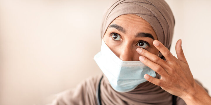 Avoid face touching, Coronavirus prevention, Doctors protection during COVID-19 pandemic. Overworked female doctor in protective face mask and hijab touching her eyes, closeup portrait