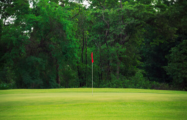 Obraz premium Golf Course Green Field with Red Flag on Putting Green in Summer for Outdoor Sport, Nature, and Tranquil Scenery