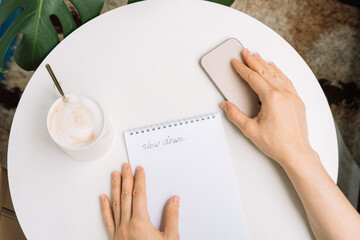Digital detox moment person reaching for phone while resting with coffee and handwritten note slow down. High quality photo