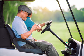 Senior Golfer Man Sitting on Golf Cart Using Smartphone During Outdoor Break on Golf Course in Summer Lifestyle Scene