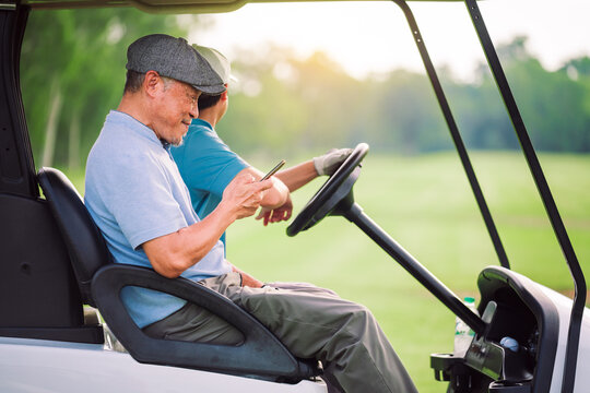 Senior Golfer Man Sitting on Golf Cart Using Smartphone During Outdoor Break on Golf Course in Summer Lifestyle Scene