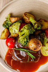 Delicious beef steak with roasted vegetables and herb sauce on a plate