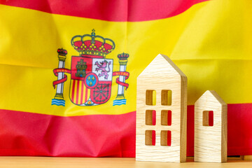 Spanish real estate. Wooden miniatures of houses against the backdrop of the Spanish flag. Economic...