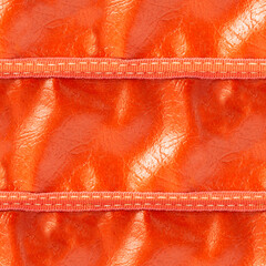Seamless 4k photo texture material of orange colored creased leather surface with stitching.
