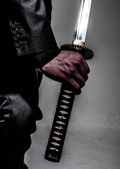 A person in a suit holding a samurai sword.