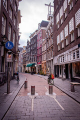 Obraz premium A narrow street in Amsterdam, lined with beautiful, colorful houses, various cafes and pubs, with bicycles parked along the way.