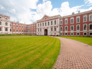 Huge court yard of Jelgava palace with well looked after grass lawn and neat footpaths, blue cloudy...