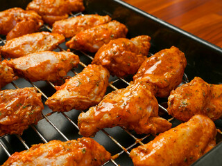 Cooking fresh chicken wings on an oven. The product is covered in red Asian style sauce and ready for cooking in high temperature. Party finger snack food.