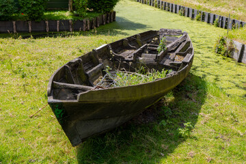 Abandoned Wooden Boat Overgrown with Weeds Beside Dutch Canal
