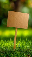 Blank cardboard sign on wooden stick in grassy outdoor setting