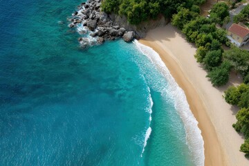 Aerial view of a beach with blue water golden sand and green trees A building stands near the treeline