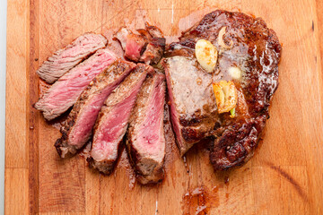 Sliced juicy medium rib eye steak on wooden board. Top view.