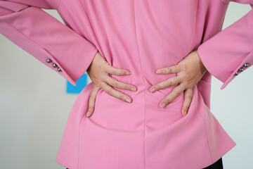 A young asian business woman is massaging and rubbing her stiff sore neck and tensed shoulder and...