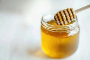 A jar filled with golden honey with a wooden honey dipper resting on top, showcasing the smooth texture and rich color of the honey.