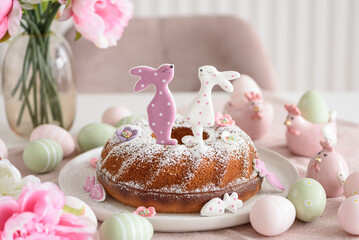 Traditional easter cakes with icing decorated with gingerbread cookies in shape of rabbits on white wooden table