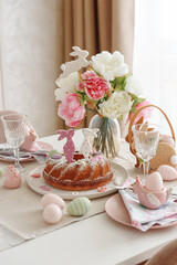 Table setting with traditional easter cakes with icing decorated with gingerbread cookies in shape of rabbits on white wooden table