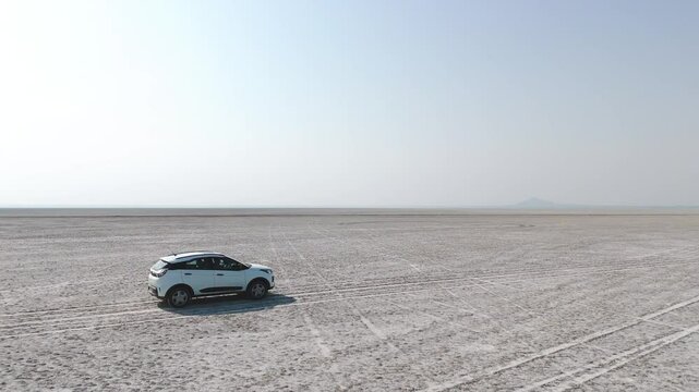 Aerial drone shot capturing the isolation of a white car in the expansive Rann of Kutch terrain.
