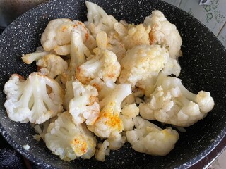 Fried golden cauliflower on hot skillet