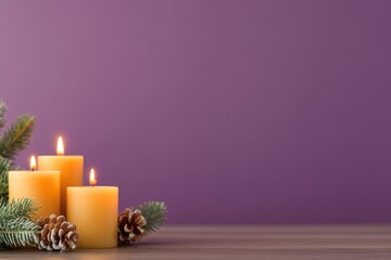 Lit candles with pine branches and cones on wooden surface against purple background