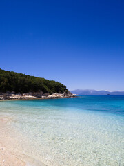 Bright beach, turquoise sea and green coastline on Kefalonia captured in a peaceful minimalist summer photo.