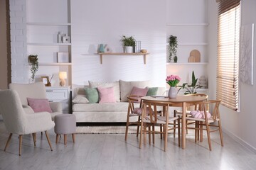 Stylish dining table with chairs and comfortable sofa in room. Interior design