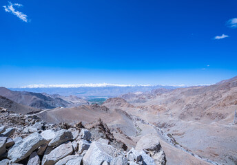snow-capped peaks and deep blue skies. White clouds float over the rugged Himalayas. The contrast...
