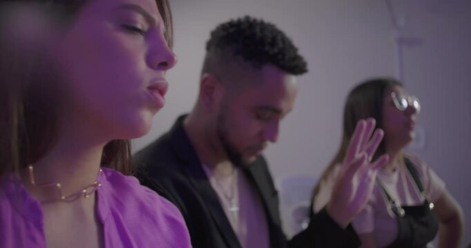 Close up of people in deep worship during evangelical church service as diverse gathering prays with eyes closed and hands lifted in spiritual unity