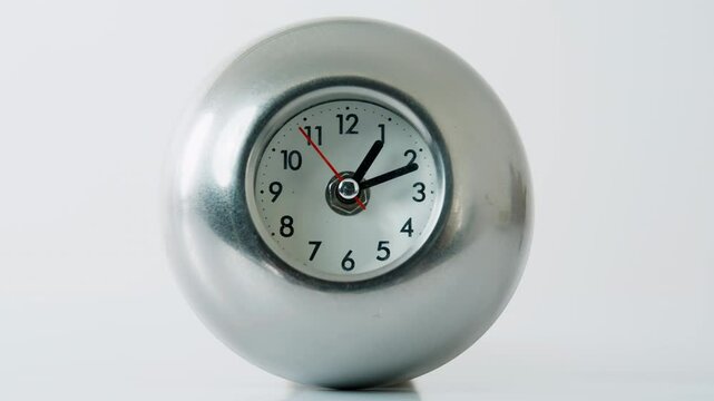 Metal clock ticking white studio space closeup. Hour and minute hands moving 