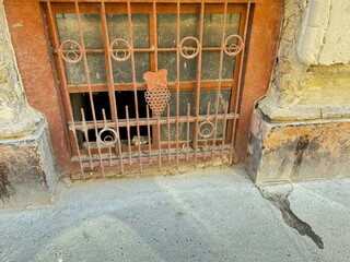 Wrought iron with a grape pattern on the basement window of a crumbling building.